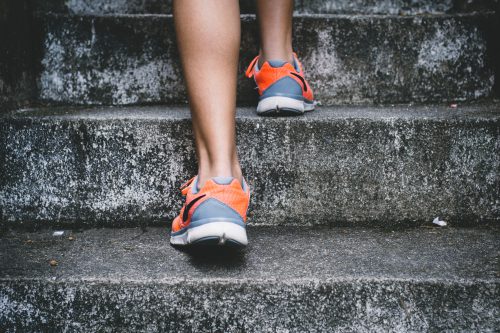 girl walking up concrete steps, wearing gray sneakers.